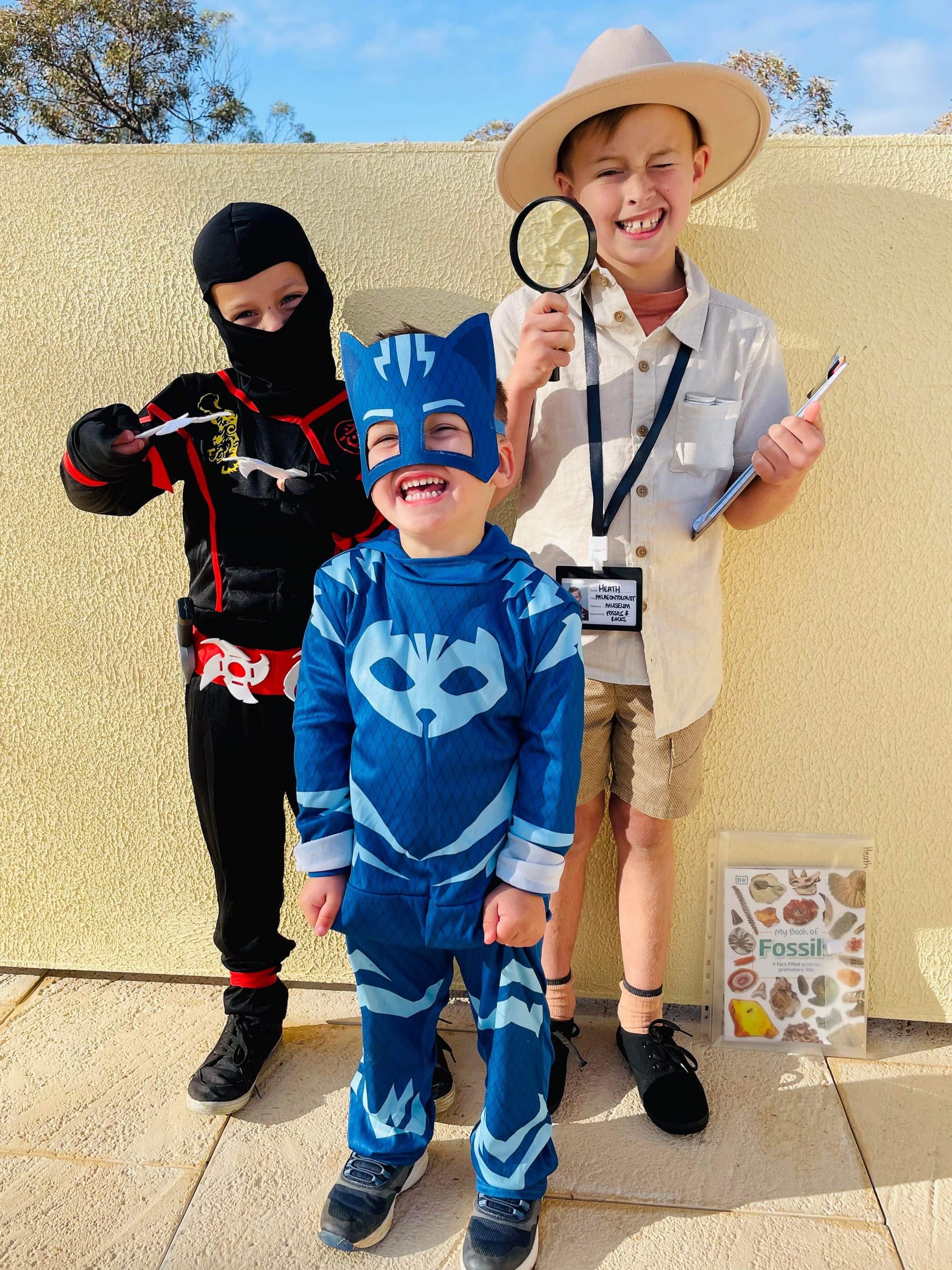 Monash Primary School students Eamon, 6, and Heath, 8, with Bodhi Porter, 3, as a ninja, palaeontologist and Catboy.